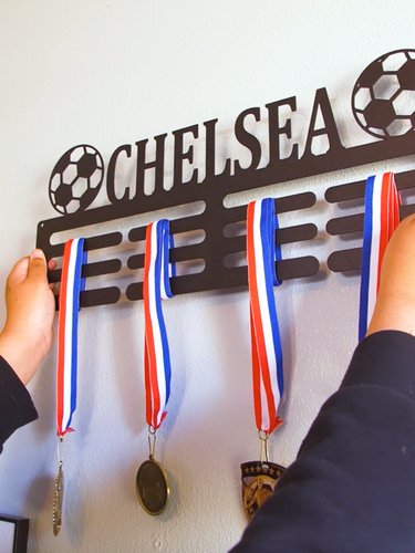 An athlete hangs a medal award hanger on their wall to showcase the awards they have won.