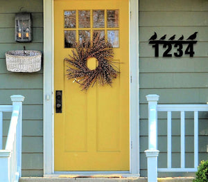 Metal exterior address sign with birds perched on numbers